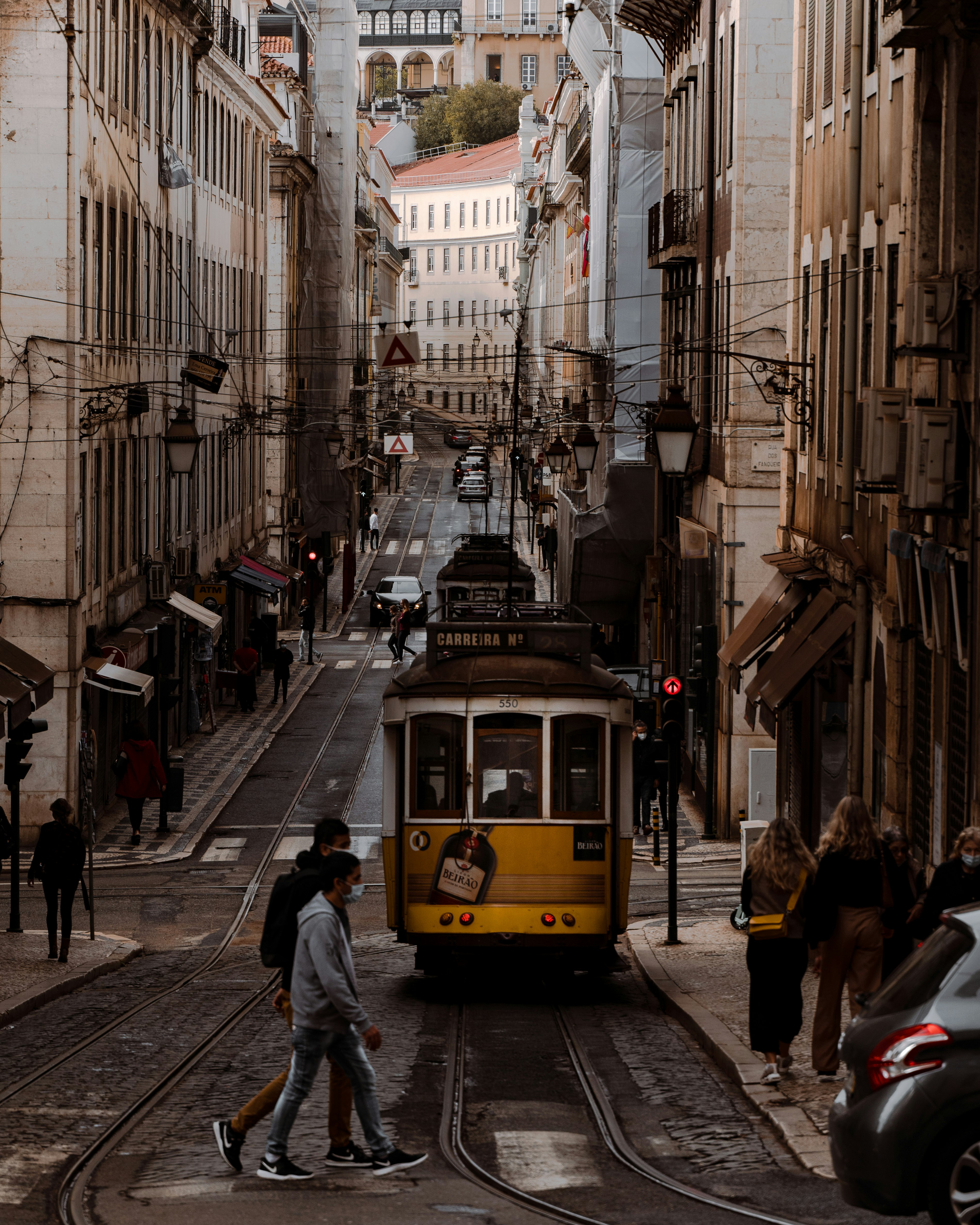 yellow tram on road between buildings during daytime